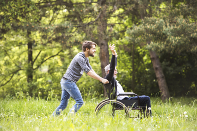 young man pushing the wheelchair while his father sitting on the wheelchair